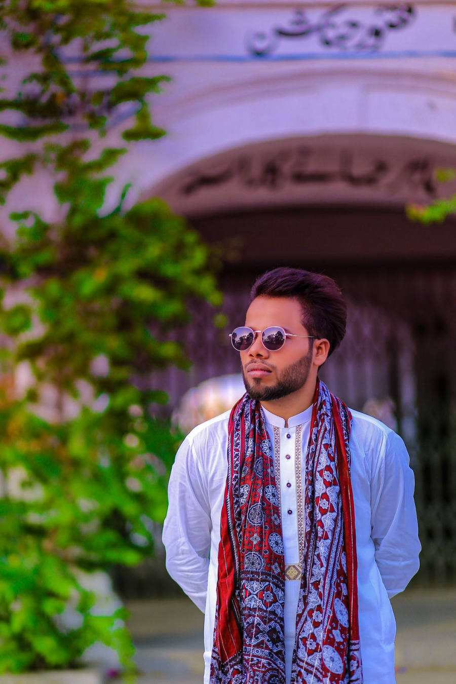 Guy in a white kurta with ajrak scarf and round sunglasses